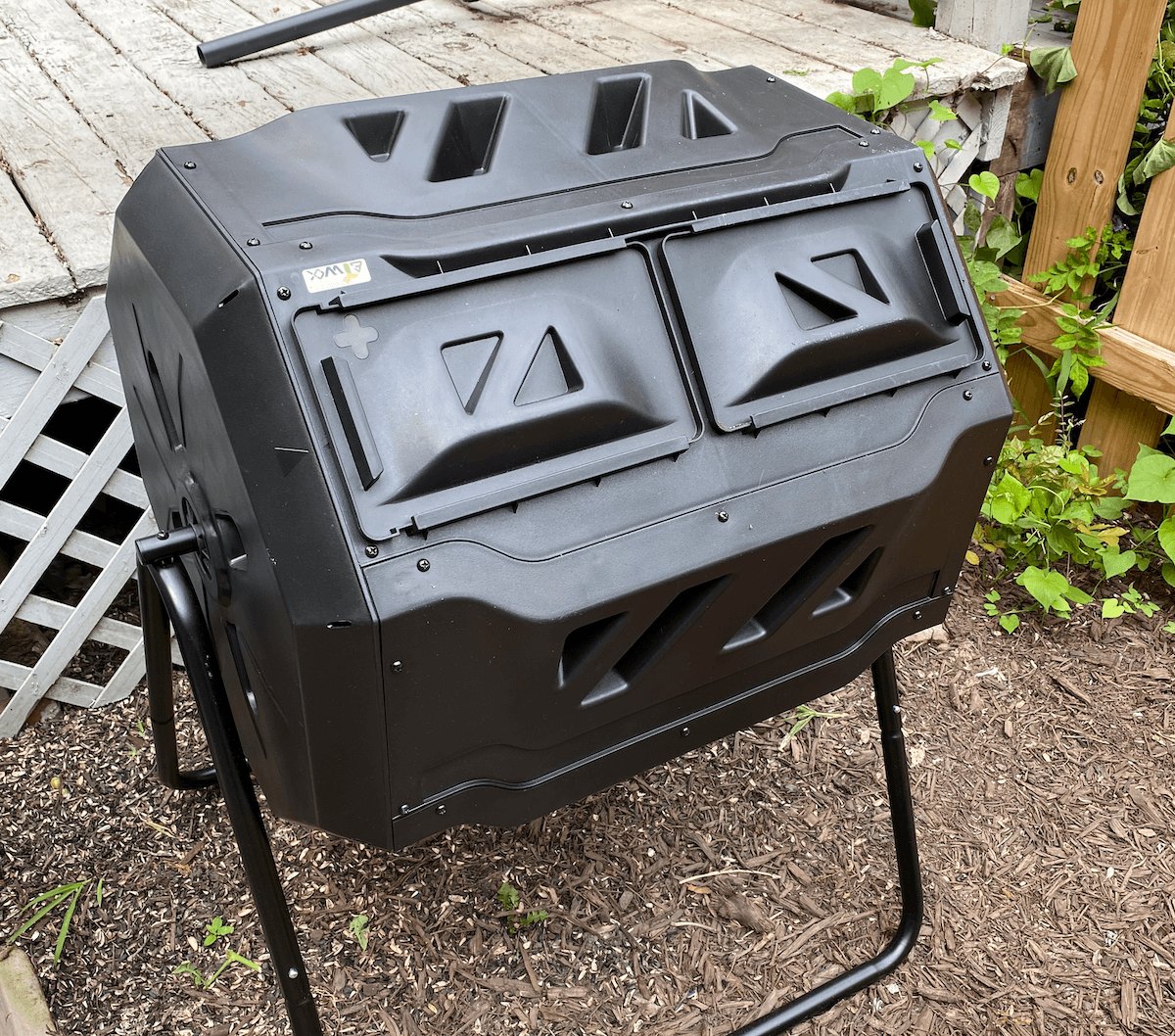 A black two-chamber tumbling composter on a stand