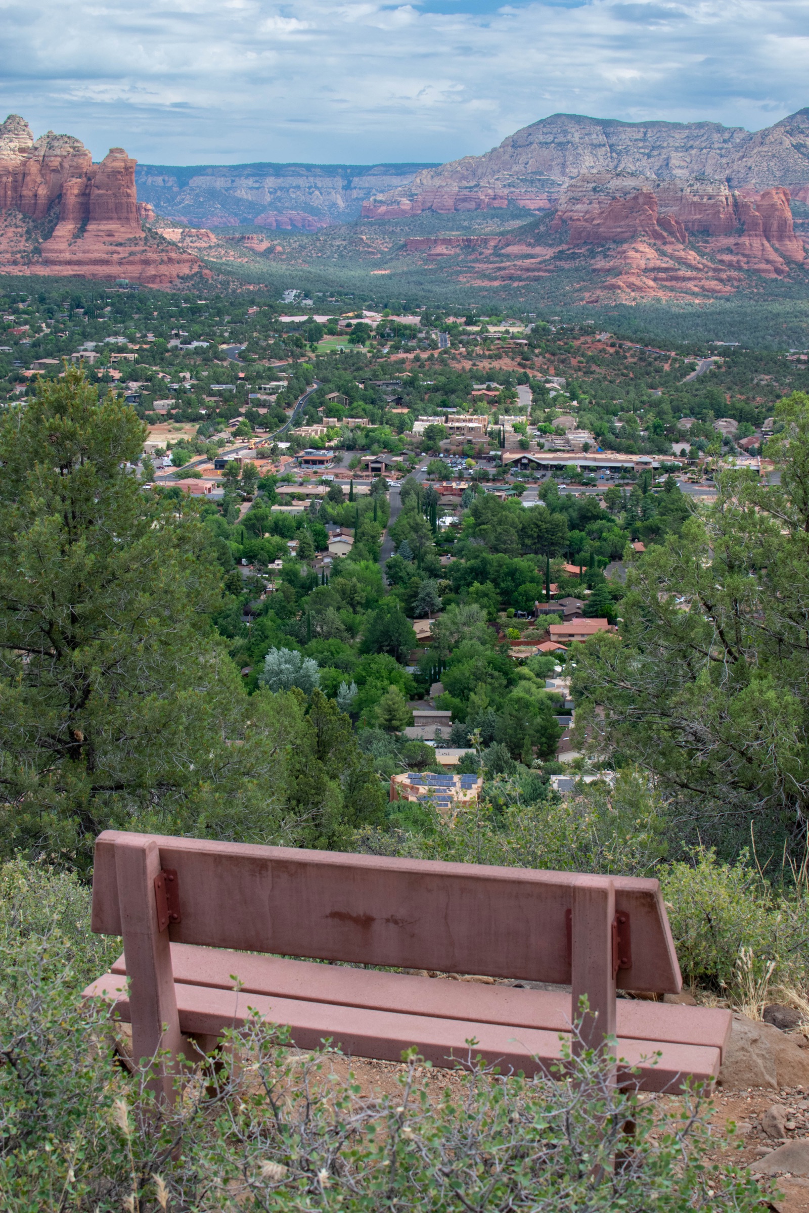 A wooden bench on a hillside overlooking Sedona and the red rock mountains beyond